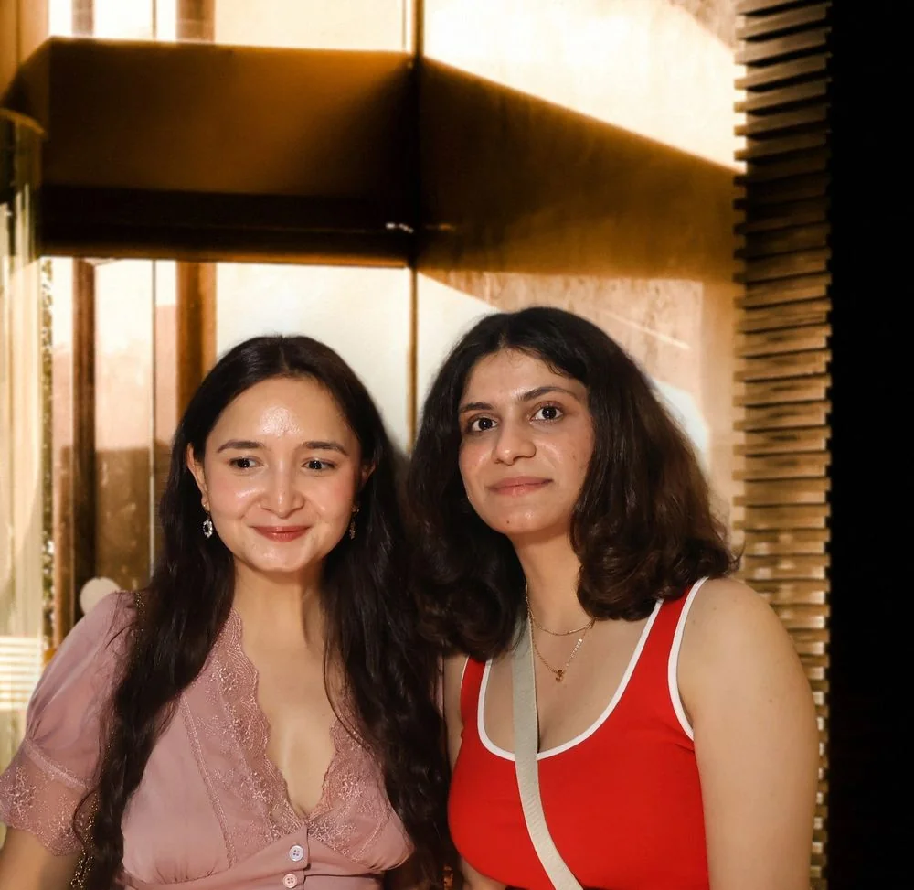 Two guests smiling side by side in warm window light at an event