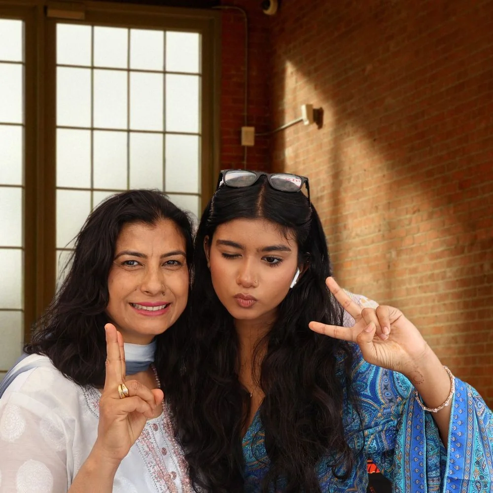 Two guests posing with peace signs against a warm brick and screen backdrop